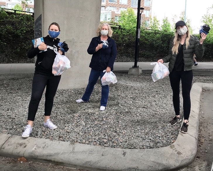 M2M grocery delivery 1 %281%29 Three masked women standing in a gravel area holding bags of groceries